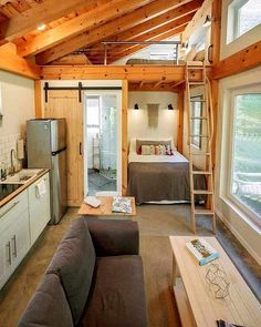 a living room filled with furniture next to a kitchen and a bedroom in the background