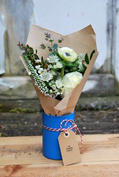 a bouquet of flowers in a blue vase on a wooden table with a price tag