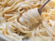 a fork is being used to stir pasta in a pan with noodle and chicken sauce