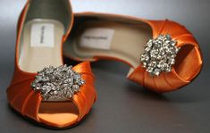 an orange pair of high heeled shoes with bows and jewel embellishments