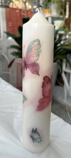 a lit candle with butterflies painted on it