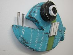 a blue and green fish shaped object hanging on a wall with screws in it