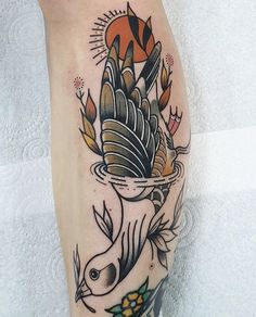 a tattoo on the leg of a person with a bird and flowers in it's beak