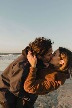 a man and woman kissing on the beach