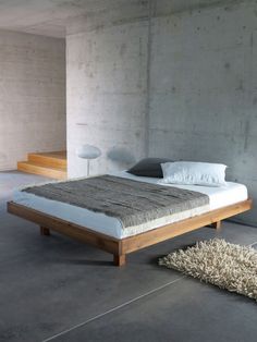 a bed sitting in the middle of a room next to a rug on the floor