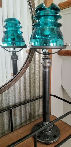 two blue glass lamps sitting on top of a wooden table next to a large mirror