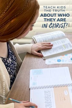 a woman sitting at a table with a book and pen in front of her, reading the truth about who they are in christ