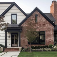 a large brick house with black trim and white siding on the front door is shown