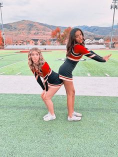 two cheerleaders are posing on the football field