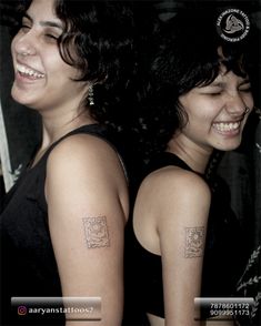 two women with tattoos on their arms smiling