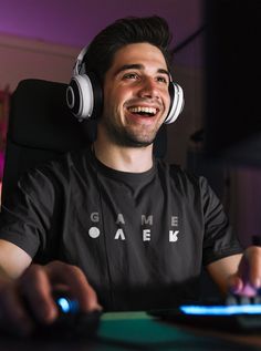 a man wearing headphones sitting in front of a computer keyboard and smiling at the camera