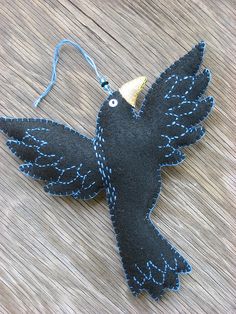 a black bird ornament hanging on a wooden table with a blue string attached to it