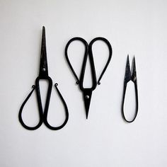 three pairs of scissors sitting next to each other on a white surface with black handles