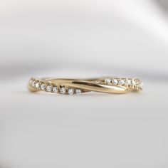 a close up view of a gold ring with diamonds on it's side, sitting on a white surface