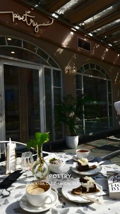 a table topped with plates and cups filled with desserts next to an open door