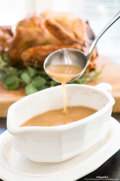 a white bowl filled with gravy next to a turkey