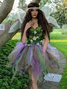 a woman dressed in a fairy costume standing next to a tree