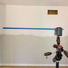 a tripod is set up in front of a wall with blue tape on it