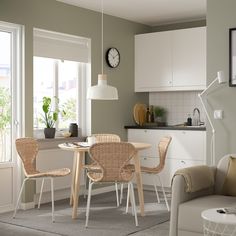 a living room and kitchen area with white cabinets, beige chairs and a round dining table