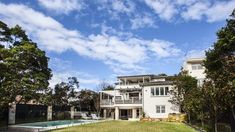 a large white house sitting next to a lush green field with trees in front of it