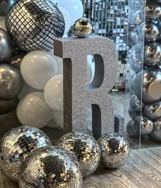 silver disco balls and balloons in front of a large letter that says p on it