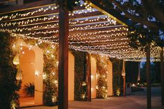 an outdoor patio covered in lights and greenery