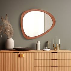 a wooden dresser topped with a mirror and vase