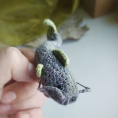 a small gray crocheted toy mouse being held by someone's hand,