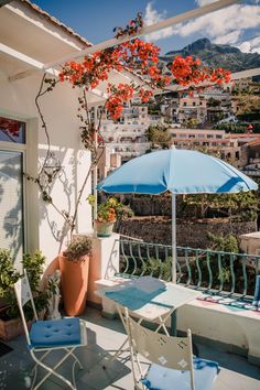 an outdoor patio with blue and white chairs, umbrellas and potted plants on the balcony