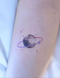 a woman's arm with a small tattoo of the planet and stars on it