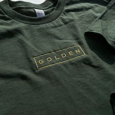 Embroidered onto a 100% cotton garment with a golden thread for a classic look. Soft-washed and garment-dyed as a forest green, the t-shirt makes for a durable staple and memento of Jungkook's first solo endeavor. This will be the softest tshirt you own! Please refer to the size guide in the listing for shirt measurements. If you have any questions or if there's a specific size/shirt color you would like but it's out of stock, please message me! I'll try my best to accommodate :) Gold Crew Neck T-shirt For Fall, Green Long Sleeve T-shirt With Embroidered Logo, Gold Short Sleeve Cotton Shirt, Gold Cotton Short Sleeve Shirt, Fall Short Sleeve T-shirt With Embroidered Logo, Relaxed Fit Gold Cotton Top, Casual Gold Cotton T-shirt, Gold Cotton Top With Relaxed Fit, Gold Crew Neck Cotton T-shirt