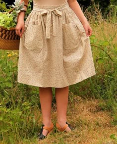 a woman is standing in the grass holding a basket