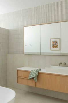 a white bath tub sitting next to a bathroom sink under two mirrors and a mirror