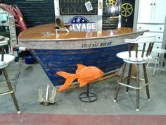 an orange fish sitting on top of a blue boat in a room filled with chairs