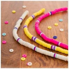 three different colored beads on a wooden table with sprinkles and buttons in the background