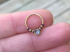 a person is holding up a gold ring with an opal stone in the middle