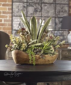 a wooden bowl filled with succulents and plants on top of a table