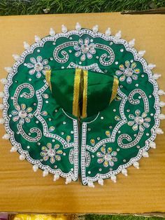 a green and white doily with gold ribbon hanging from it's center piece