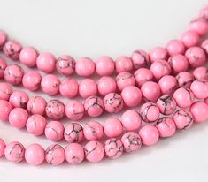 three strands of pink beads with black speckles