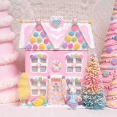 a pink doll house surrounded by christmas trees