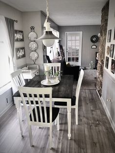 a dining room table with chairs and pictures on the wall behind it in black and white