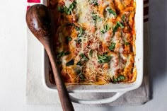 a casserole dish with cheese, spinach and parmesan on top