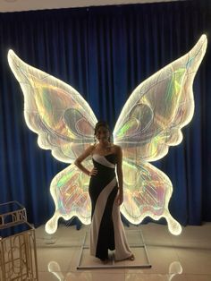 a woman in a black and white dress standing next to a large butterfly shaped object