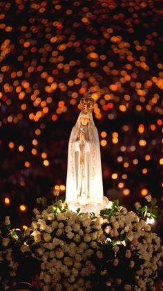 the statue is surrounded by flowers and lights