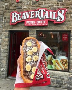 a person is holding up a pastry in front of a storefront with bananas on it