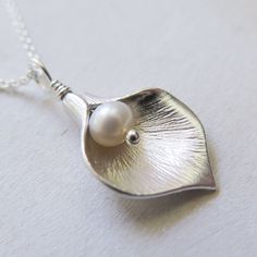 Silver Calla Lily Necklace - Gift for Her Classic and elegant gift for mother, friend or for bridesmaids. Dainty, easy to wear everyday or on special occasions. FEATURES: * A small freshwater pearl is wire wrapped with bright calla lily petal to form a flower pendant. * The petal is rhodium plated over brass. * Comes with sterling silver chain, finished with spring clasp closure. All sterling silver calla lily necklace: https://www.etsy.com/listing/476943360/ MEASUREMENTS: * the pendant is about Elegant White Necklace - Gift For Mom, Elegant Handmade Necklace Gift For Mom, Elegant Handmade Necklace For Mom, Elegant Nickel-free Necklace For Wedding, Elegant Flower Shaped Necklace For Mom, Elegant White Jewelry For Mom's Gift, Elegant White Jewelry As Gift For Mom, Elegant White Jewelry As A Gift For Mom, Elegant Nickel-free Necklaces For Bridesmaid Gift