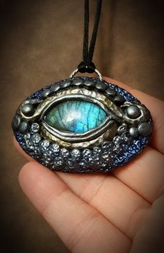 "**insurance included free of charge on all orders of $50 or more This Ice Dragon pendant is a part of my Dragonfire collection, which embodies the strength, beauty, magic, and fire of dragons! This stylized Ice Dragon pendant was created and sculpted from polymer clay to look like a dragon eye, using a gorgeous blue flash Labradorite cabochon as the focal \"eye\" stone! It was colored with blue, silver, and crystal pigments to give this an icy feel! This was also sealed upon completion! This wa Handmade Fantasy Round Pendant Jewelry, Fantasy Style Handmade Round Pendant Jewelry, Handmade Polymer Clay Jewelry In Fantasy Style, Spiritual Polymer Clay Pendant Necklace, Handmade Fantasy Jewelry Gift, Handmade Fantasy Jewelry As A Gift, Handmade Polymer Clay Round Pendant Jewelry, Artistic Polymer Clay Jewelry For Gift, Fantasy Polymer Clay Jewelry As A Gift