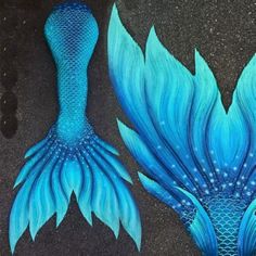 two blue mermaid tail sculptures sitting on the ground