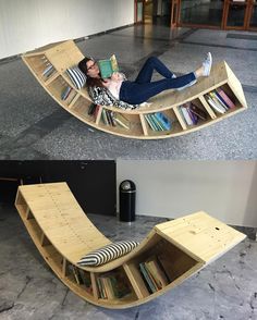 a woman laying on top of a wooden boat shaped book shelf next to a black trash can