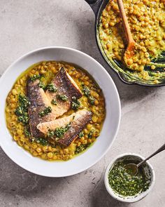 two bowls filled with fish and vegetables next to a pot of pesto on the table